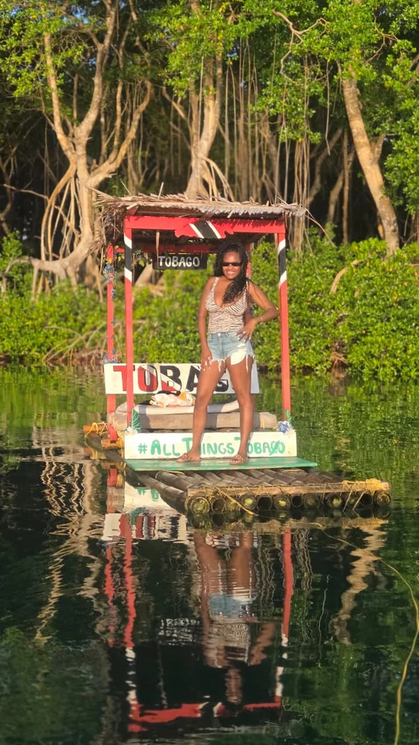 Leslieann standing on a bamboo raft surrounded by mangroves and reflected in the water
