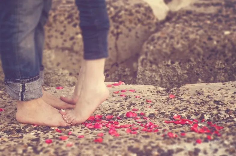 Bare feet standing on flower petals outdoors