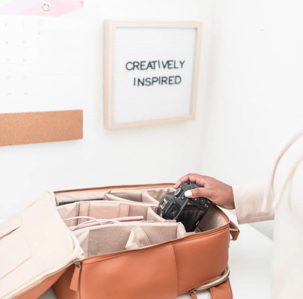 Camera in an open bag beneath a sign reading “Creatively Inspired”